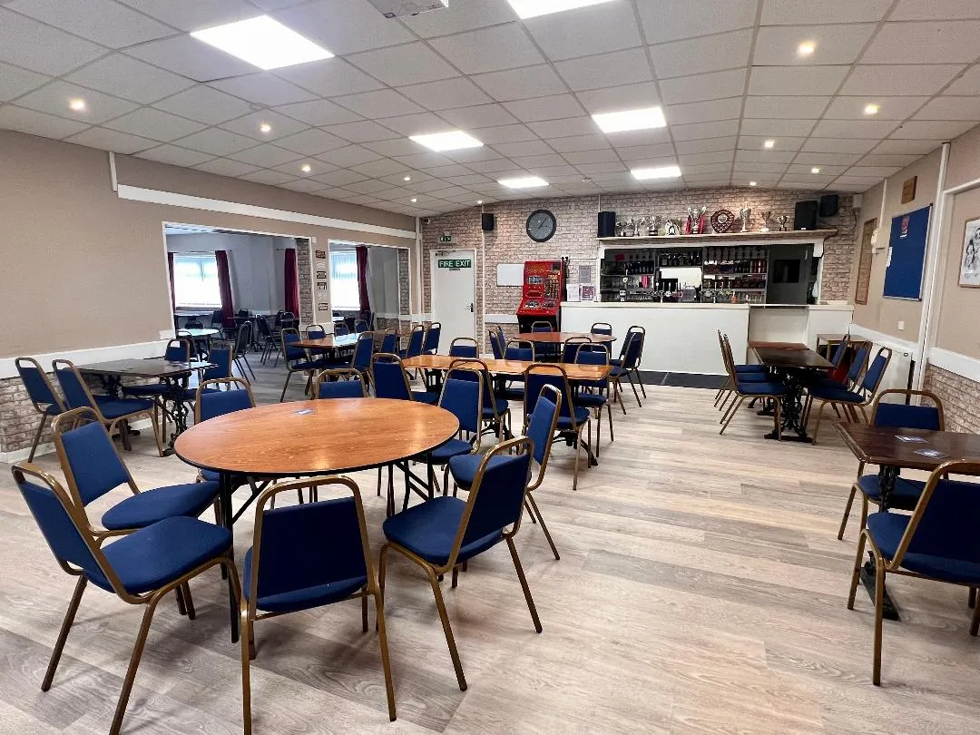 The bar area inside the centre: round tables and blue chairs in front of a bar counter lined with trophies.